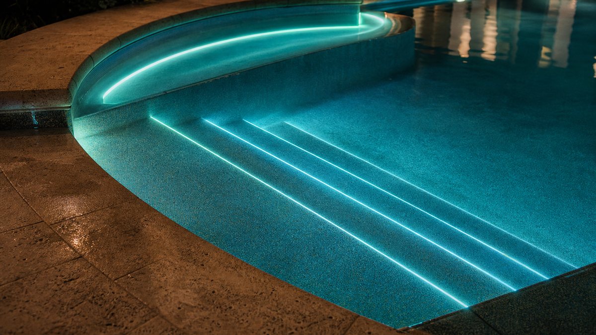 Community pool steps and bench outlined with glowing fiber optic lighting at night